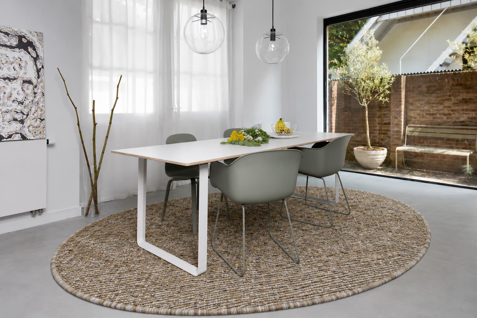 Ovaal wollen vloerkleed Diane met gemêleerde bolletjesstructuur onder moderne eettafel